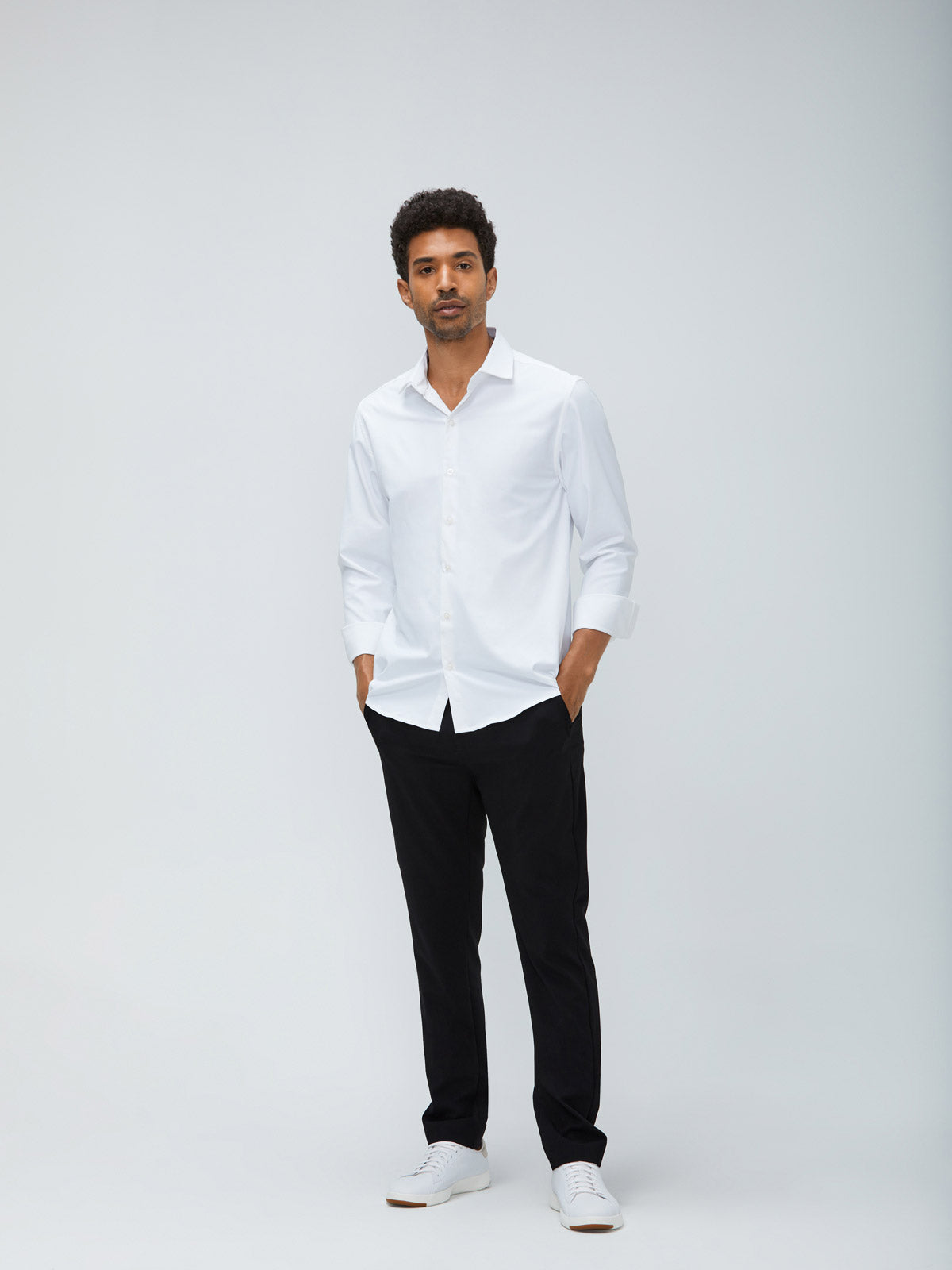 Men's White Aero Zero Dress Shirt and Men's Black Velocity Pant on Model facing forward with hands in pants pockets