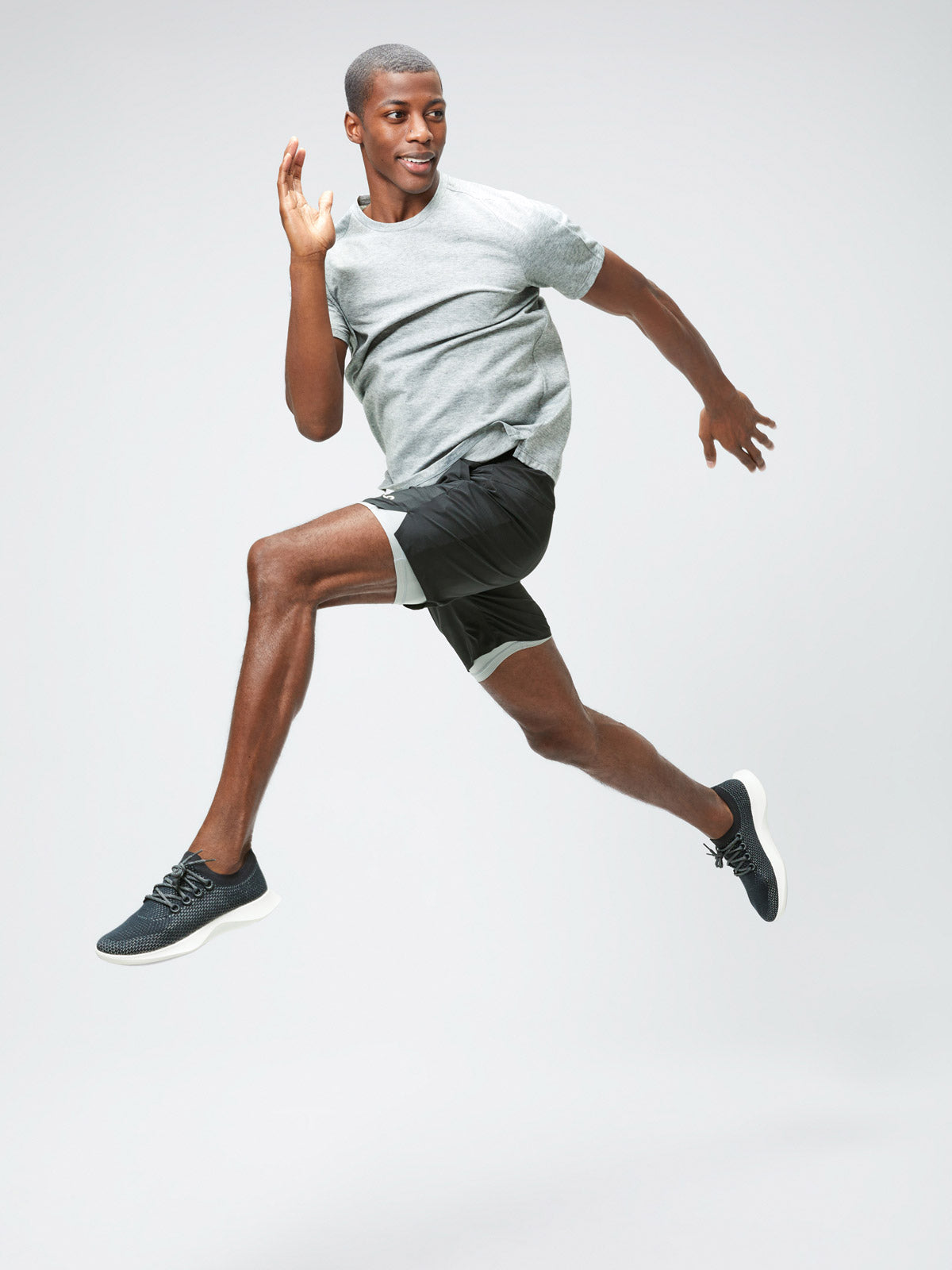 Men's Charcoal Grey Heather Composite Merino Active Tee and Men's Black Newton Active Shorts on model jumping in air