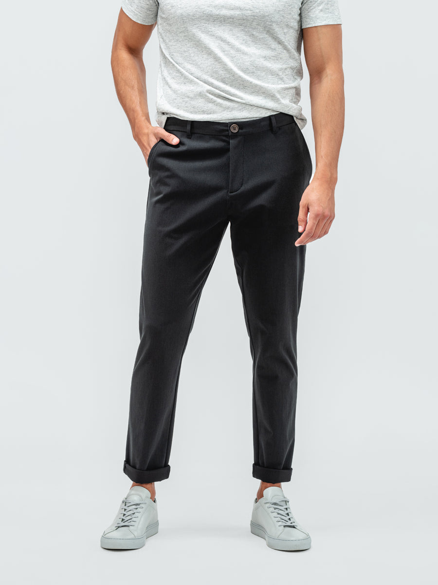 Man with his hand in pocket wearing the pace tapered chino in black with grey sneakers