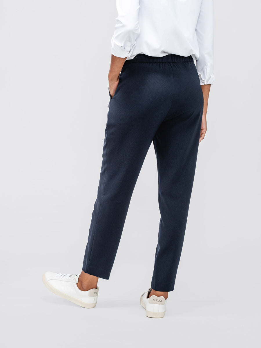 Back of Women's Navy Swift Drape Pant on model with hand in pocket