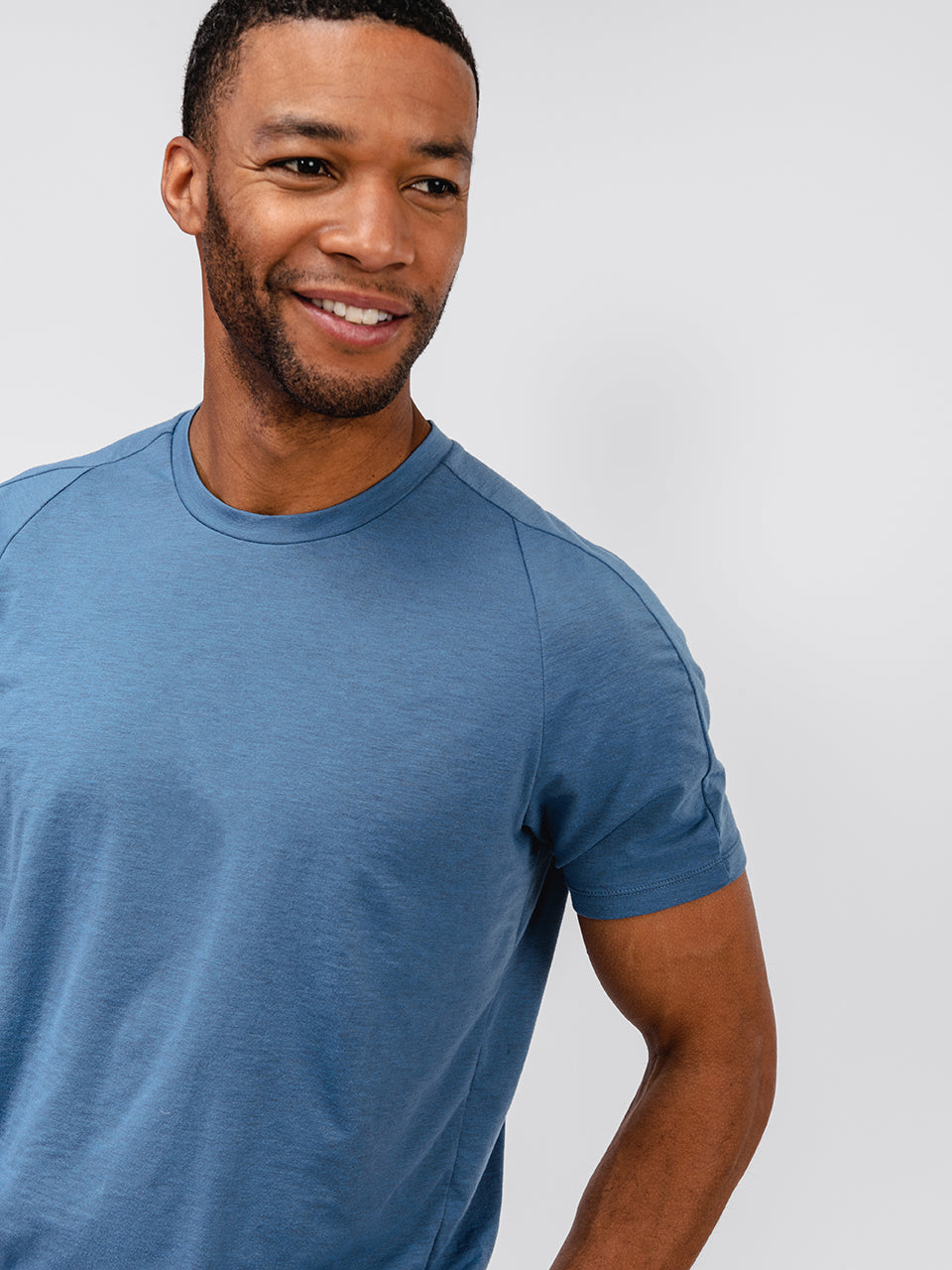 model wearing composite merino tee stone blue looking sideways