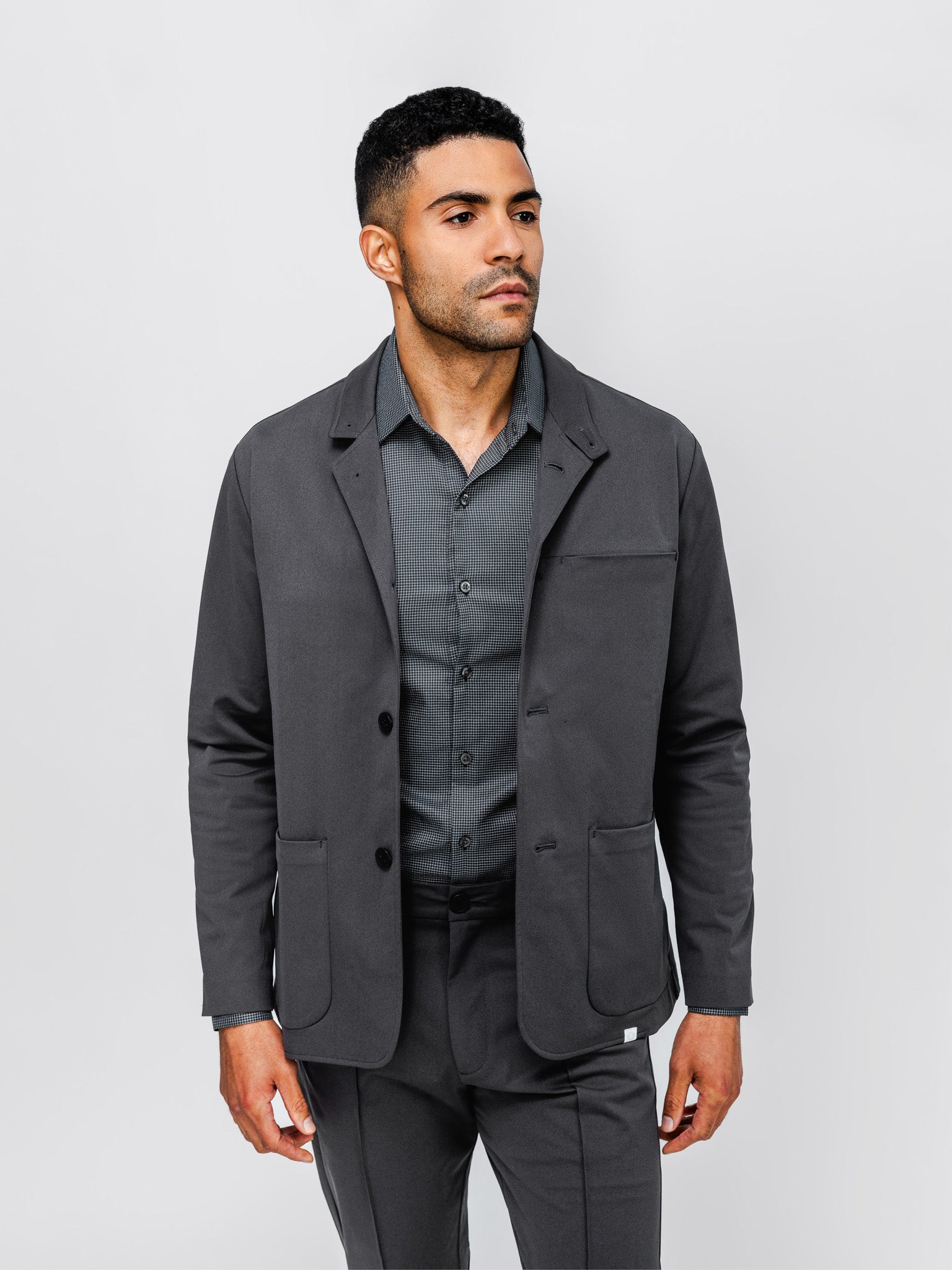 model wearing mens kinetic pintuck pant charcoal and mens kinetic chore blazer charcoal and mens aerozero dress shirt charcoal mini grid